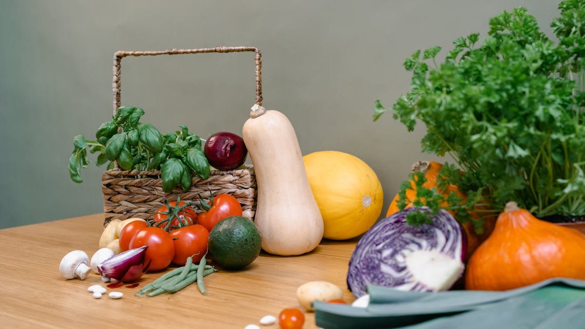 Assorted fresh vegetables and herbs on a wooden table enhancing culinary inspiration.